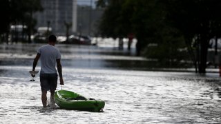 Man stands in high waters in the aftermath of a hurricane.