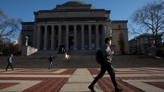 In this March 9, 2020, file photo, a man walks past Low Library on the Columbia University campus in New York.