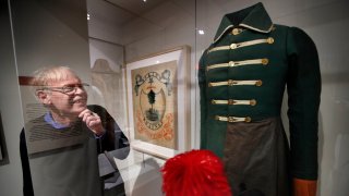 In this Friday, March 13, 2020 photo, State historian Earle Shettleworth examines a First Maine Militia uniform, probably worn by a soldier from Buckfield, on display at the Maine State Museum in Augusta, Maine.
