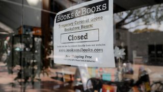 A sign on locally owned business Books & Books says the store is closed during the coronavirus pandemic, Thursday, April 9, 2020, in Miami.
