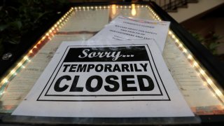 In this April 28, 2020, file photo, a closed sign is posted at a restaurant along the River Walk in San Antonio.
