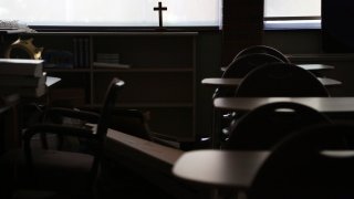 A cross sits in the window of an empty classroom at Quigley Catholic High School in Baden, Pa.