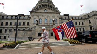 Don Hartness of Ellisville, walks around the Capitol carrying the current Mississippi state flag