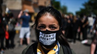 A woman poses as she wears a mask saying "I can't breathe"