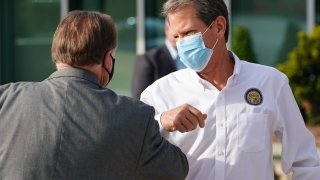 Brian Kemp, governor of Georgia, wears a protective mask while bumping elbows with an attendee during a 'Wear A Mask' tour stop in Dalton, Georgia, on July 2, 2020.