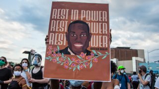 In this May 30, 2020, file photo, a protester holds a George Floyd placard during the protest in response to the death of African American George Floyd at the hands of Minneapolis, Minnesota in the Brooklyn borough of New York City.