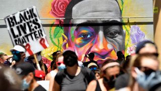 Marchers walk by a mural of George Floyd painted on a wall along Colfax Avenue on June 7, 2020, in Denver, Colorado.