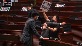 Pan-democratic legislator Chan Chi-chuen holding a placard reading "A murderous regime stinks for ten thousand years" scuffles with security guards at the main chamber of the Legislative Council dropping a pot of a pungent liquid in the chamber in Hong Kong, Thursday, June 4, 2020.