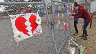 In this April 20, 2020, file photo, a woman and her daughter place a heart at a growing memorial in front of the Debert School in Debert, Nova Scotia, Canada.