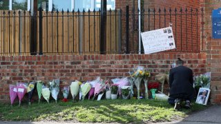 Flower tributes are placed at the entrance to Holt School in Wokingham, England, in memory of teacher James Furlong, a victim of a terror attack in nearby Reading, Monday June 22, 2020. A lone terror suspect remains in custody accused of killing three people and wounding three others in a Reading park on Saturday night.