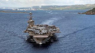 In this June 4, 2020, photo provided by the U.S. Navy, the aircraft carrier USS Theodore Roosevelt (CVN 71) departs Apra Harbor in Guam. The carrier has returned to sea and is conducting military operations in the Pacific region 10 weeks after a massive coronavirus outbreak sidelined the Navy warship.
