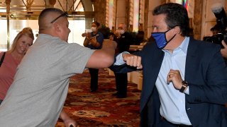 MGM Resorts International Acting CEO and President Bill Hornbuckle (R) bumps elbows with one of the first guests to arrive at Excalibur Hotel & Casino as the Las Vegas Strip property opens for the first time since being closed in mid-March because of the coronavirus pandemic, June 11, 2020, in Las Vegas, Nev.