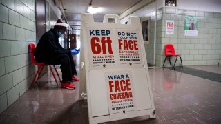 A sign reminds voters to practice social distancing during the election to fill the remainder of the late Rep. Elijah Cummings' term, April 28, 2020, at Edmondson High School in Baltimore, Md.