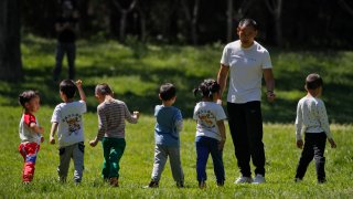 In this May 11, 2020, file photo, children accompanied by a man play at a public park as kindergarten and primary schools remain closed following the coronavirus outbreak in Beijing, China.