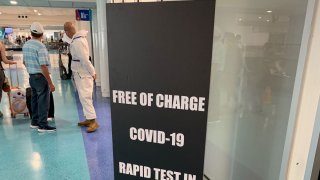 Workers steer travelers toward free testing for COVID-19 antibodies at Puerto Rico's main airport in San Juan on June 28, 2020.