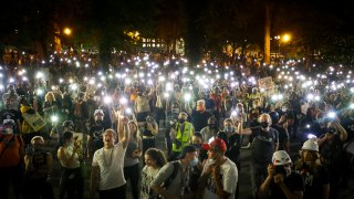 Demonstrators raise their cell phone lights as they chant slogans during a Black Lives Matter protest at the Mark O. Hatfield United States Courthouse Wednesday, July 29, 2020, in Portland, Ore.