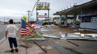 Dustin Amos walks near debris at a gas station on Thursday, Aug. 27, 2020, in Lake Charles, La., after Hurricane Laura moved through the state.