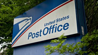 Signage stands outside a United States Postal Service (USPS) facility in Fairfax, Virginia, U.S., on Tuesday, May 19, 2020. The Postal Service in recent weeks has sought bids from consulting firms to reassess what the agency charges companies such as Amazon, UPS and FedEx to deliver products on their behalf between a post office and a customer's home, the Washington Post reported last week.