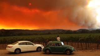 Local residents sit next to a vineyard as they watch the LNU Lightning Complex fire burning in nearby hills on August 20, 2020 in Healdsburg, California.