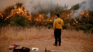 Kings County firefighter Edgar Morales watches as as a backfire burns off Chemise Road in Healdsburg, Calif., on Tuesday, Aug. 25, 2020.