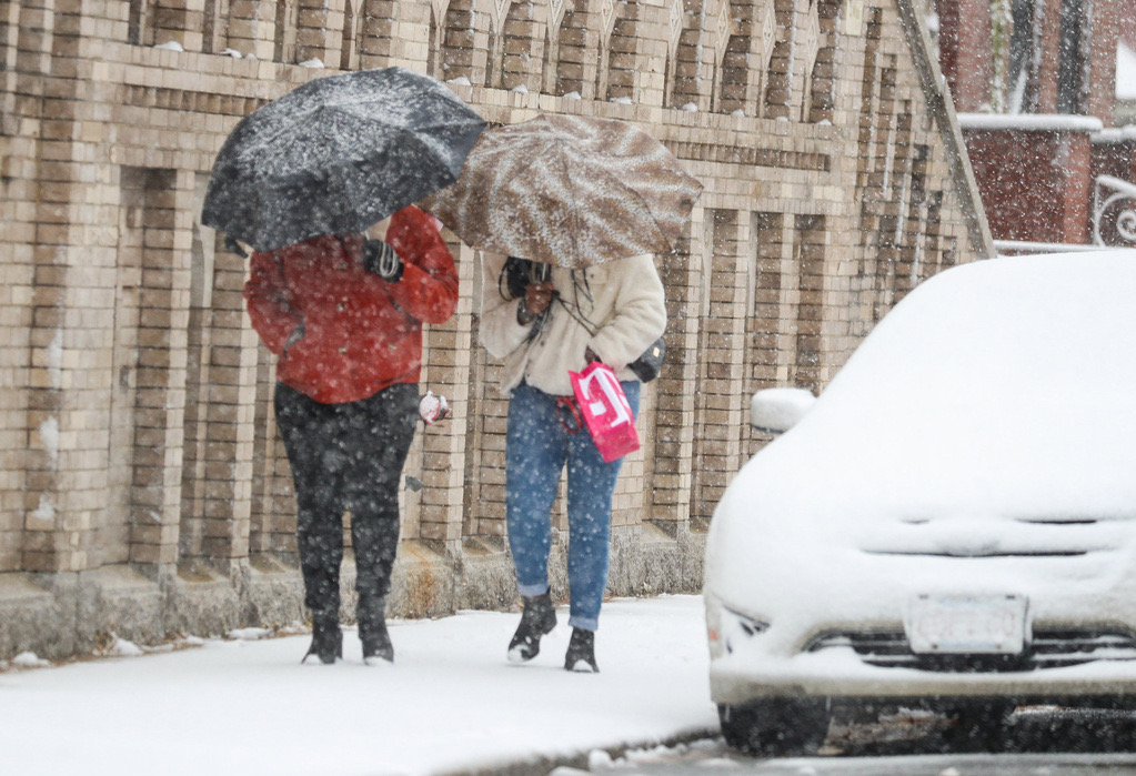 Two pedestrians in East Boston, Mass. with umbrellas.