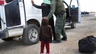 A child watches as a U.S. Border Patrol agent searches a Central American immigrant