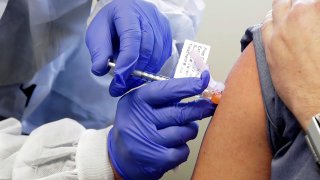 In this March 16, 2020, file photo, a subject receives a shot in the first-stage safety study clinical trial of a potential vaccine by Moderna for COVID-19, the disease caused by the new coronavirus, at the Kaiser Permanente Washington Health Research Institute in Seattle.