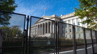 In this Nov. 3, 2020, file photo, the building of the U.S. Treasury Department can be seen behind the fence that provides extensive security for the White House on the day of the presidential election.
