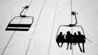 People on a Vermont ski lift are seen in silhouette in the snow