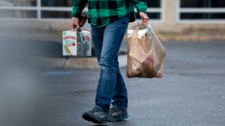 A man carry his groceries out of a Maine Hannaford in a plastic bag.