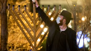 A member of Chabad of Midtown lights the first candle of Hanukkah in the Hudson Yards in New York City