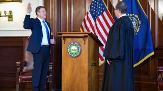 New Hampshire Gov. Chris Sununu holds his hand up as he is sworn in on Thursday, Jan. 7, 2021.
