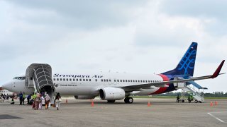 This picture taken on September 3, 2019, shows passengers boarding a Sriwijaya Air Boeing 737-800 aircraft at the airport in Padang, West Sumatra.