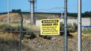 In this Wednesday, Aug. 14, 2019 photo, a sign at the Hanford Nuclear Reservation warns of possible hazards in the soil there along the Columbia River near Richland, Wash. Washington state officials are worried that the Trump administration wants to reclassify millions of gallons of wastewater at Hanford from high-level radioactive to low-level, which could reduce cleanup standards and cut costs.
