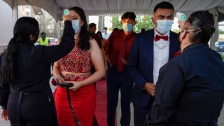 Grace Gardens Event Center employees check temperatures of young people attending prom at the Grace Gardens Event Center in El Paso, Texas, on May 7, 2021. Around 2,000 attended the outdoor event at the private venue after local school districts announced they would not host proms this year.