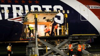 Workers unload coronavirus vaccines from the New England Patriots' plane in El Salvador on Wednesday, May 19, 2021.
