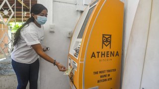 A woman withdraws money from an Athena Bitcoin ATM.