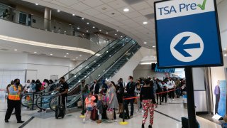 Passengers wearing protective masks wait in lines to pass through a TSA checkpoint at Hartsfield-Jackson Atlanta International Airport in Atlanta, Georgia.