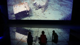 BELFAST, NORTHERN IRELAND - MARCH 27: Visitors look at a projection showing images of the wreck of the Titanic on the seabed at the Titanic Belfast visitor attraction on March 27, 2012 in Belfast, Northern Ireland. The Titanic Belfast Experience is a new £90 million visitor attraction opening on March 31, 2012. One hundred years ago the maiden voyage of the ill-fated passenger liner Titanic sank after hitting an iceberg in the Atlantic on the night of April 14, 1911 with the loss of 1517 lives.