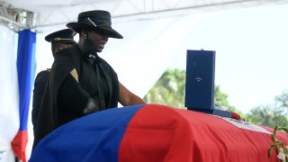 Martine Moise stands over the casket, draped in the blue and red flag of Haiti.