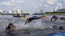 Morgan Pearson of the United States, center, dives into the water for the start of the men's individual triathlon at the 2020 Summer Olympics on July 26, 2021, in Tokyo, Japan.