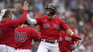 Boston Red Sox's Enrique Hernandez, center, celebrates with teammates after scoring on a sacrifice fly by Xander Bogaerts in the eighth inning of a baseball game against the New York Yankees, Sunday, July 25, 2021, in Boston. The Red Sox won 5-4.