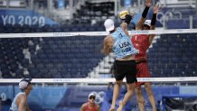 Jacob Gibb, top left, of the United States, takes a shot as Adrian Heidrich, of Switzerland, defends during a men's beach volleyball match at the 2020 Summer Olympics, Wednesday, July 28, 2021, in Tokyo, Japan.