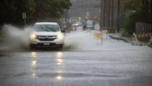 A car makes a huge splash driving on the flooded streets