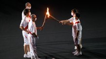 Torch carriers exchange the flame of the Olympic torch during the Opening Ceremony of the Tokyo 2020 Olympic Games at Olympic Stadium on July 23, 2021 in Tokyo, Japan.