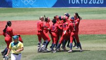Team United States players mob teammate Amanda Chidester #4 after she hit a two-run RBI single in the eighth inning to win the game 2-1 as Stacey Mcmanus #4 of Team Australia looks on after their game during the Softball Opening Round on day two of the Tokyo 2020 Olympic Games at Yokohama Baseball Stadium on July 25, 2021, in Yokohama, Kanagawa, Japan.