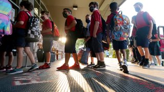 Wearing masks to prevent the spread of COVID-19, elementary school students line up to enter school for the first day of classes in Richardson, Texas, Tuesday, Aug. 17, 2021. Despite Texas Gov Greg Abbott's executive order banning mask mandates by local officials, the Richardson Independent School District and many others across the state are requiring masks for students.