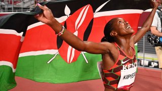 Kenya's Faith Kipyegon celebrates with her national flag after winning the gold medal in the women's 1500m final during the Tokyo 2020 Olympic Games