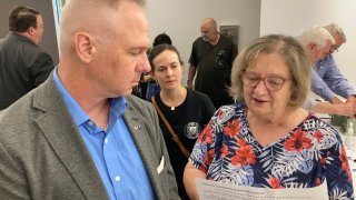 Brian Stransky, of unincorporated Sarpy County, Nebraska, listens as Citizens for Voter ID campaign official Nancy McCabe reads to him from a voter ID ballot petition