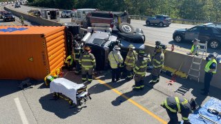 Firefighters work to free a driver after a truck crash on the Massachusetts Turnpike